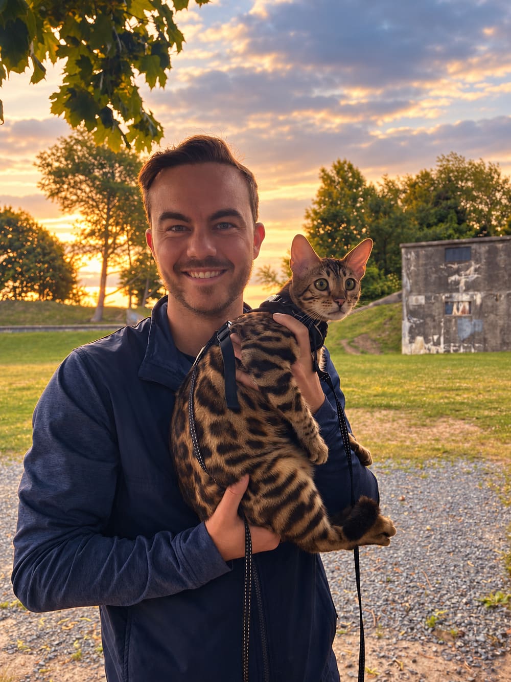 Riley holding his Bengal cat outdoors at sunset