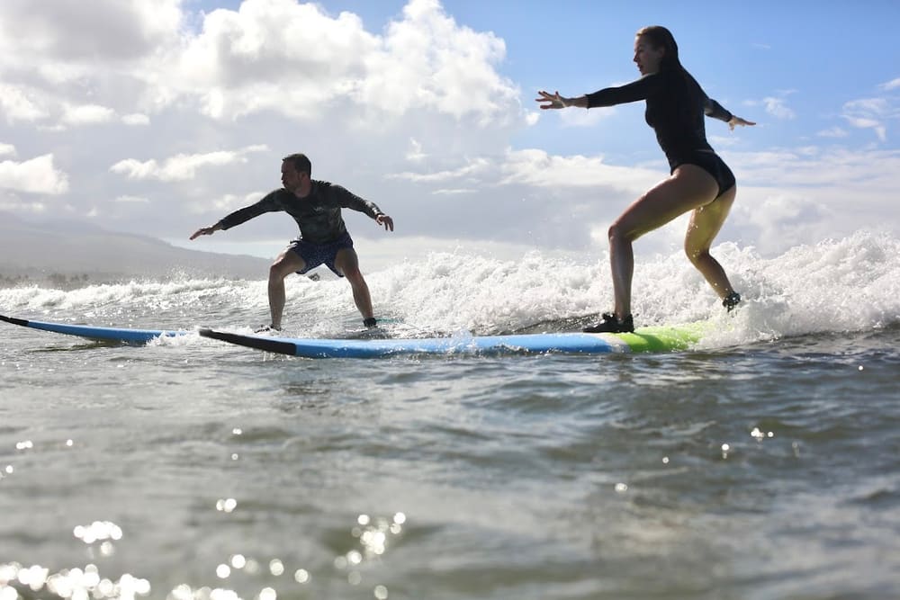 Riley and a friend surfing small waves on longboards
