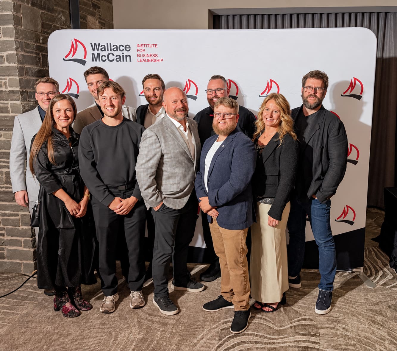 Riley with his Wallace McCain Institute cohort in front of the institute banner